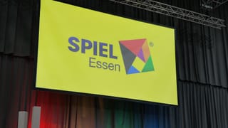 Bühne der SPIEL-Essen-Pressekonferenz 2026 mit dem SPIEL-Essen-Logo auf der großen Leinwand